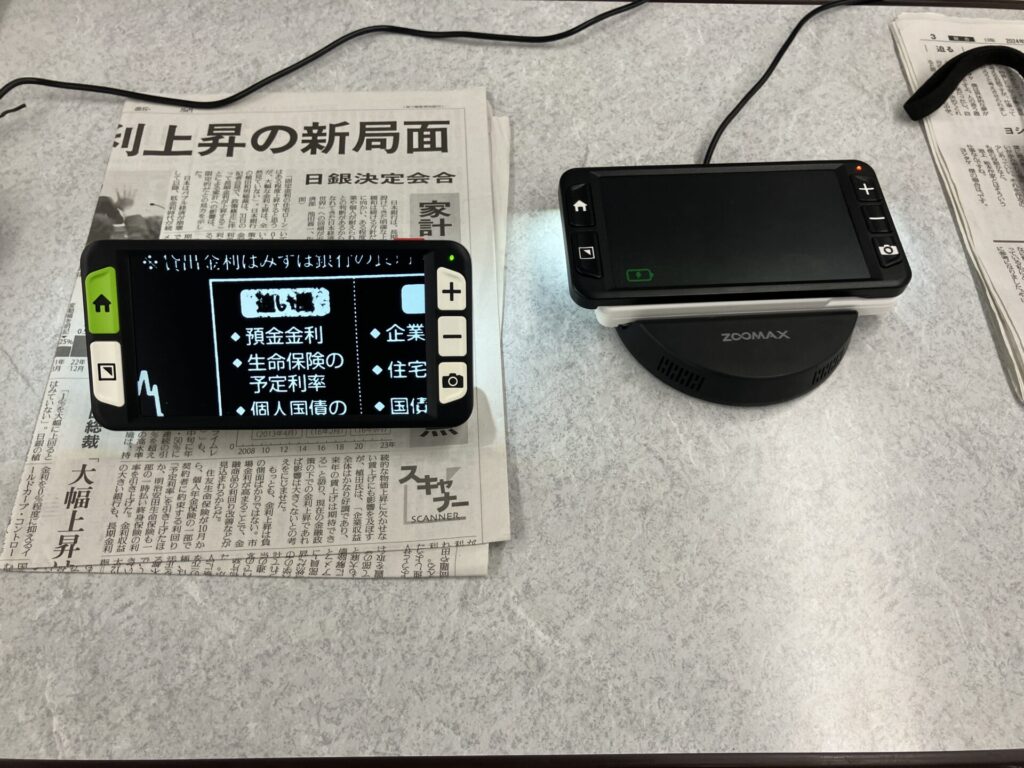 携帯型拡大読書器ルナ6とルナSを机の上に置いて充電と書類をルナ6に映しています。